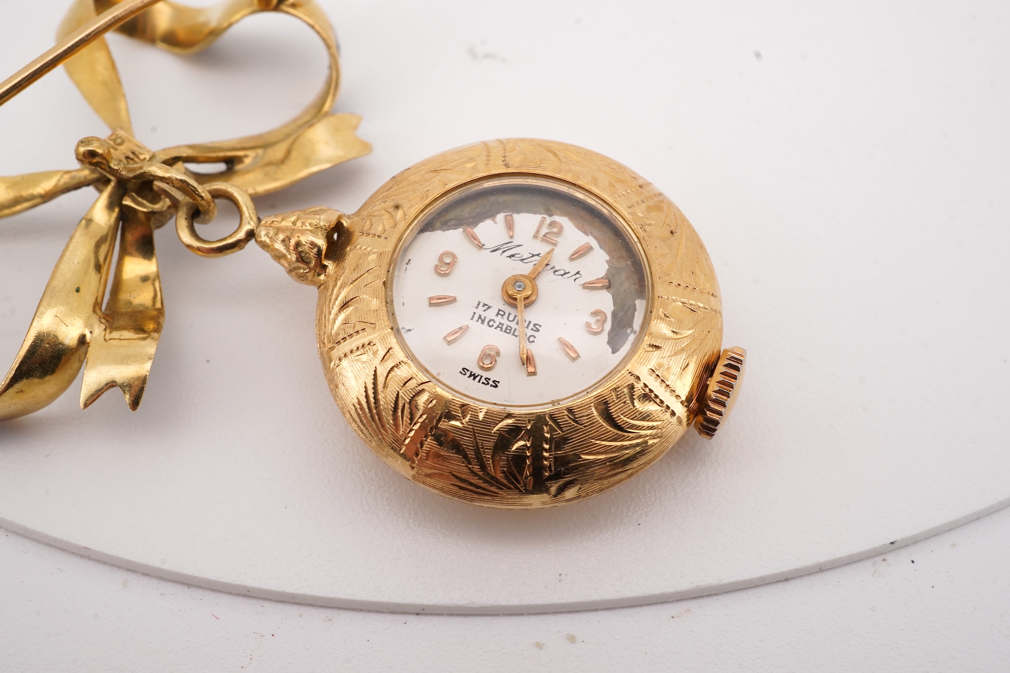 A mid 20th century Italian 18k and enamel fob watch, dial a.f., suspended from and Italian 18k and blue enamelled ribbon bow brooch, brooch width 30mm.